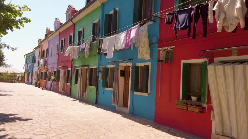 shot of colorful houses in Burano with a clothesline which hangs on the window and in front of the house at sunny weather, Italy
