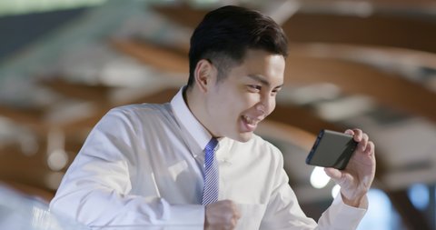 businessman watch sport game with the phone and feel excited