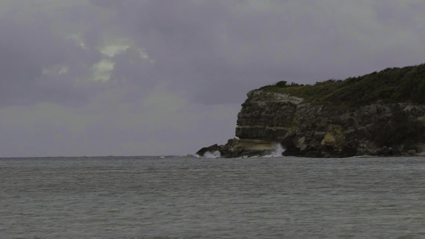 Waves crashing into rock cliffs of a small island off the coast of Vieques Puerto Rico during golden hour of a sunset on a cloudy spring evening