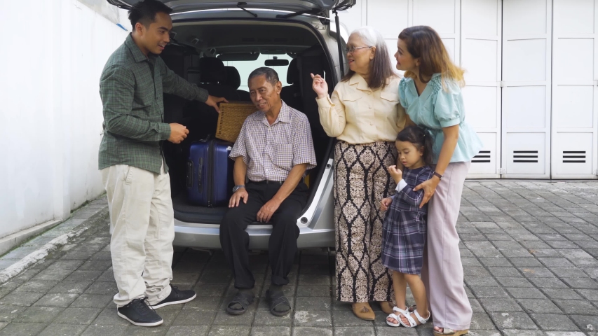 Happy three generation family preparing luggage for traveling while chatting behind the car. Shot in 4k resolution | Shutterstock HD Video #1030222955