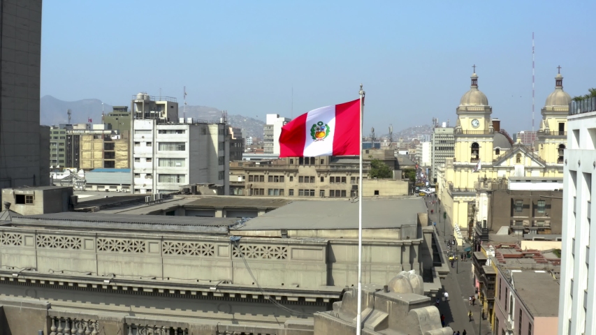 Peruvian flag waving against buildings in the historic center of Lima, the capital of Peru. Patriotism and nationalism concepts.