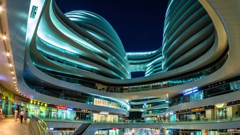 Beijing, China - June 26, 2018: Zoom out time lapse view of modern architectural landmark Galaxy SOHO Mall at night in Beijing, China. 