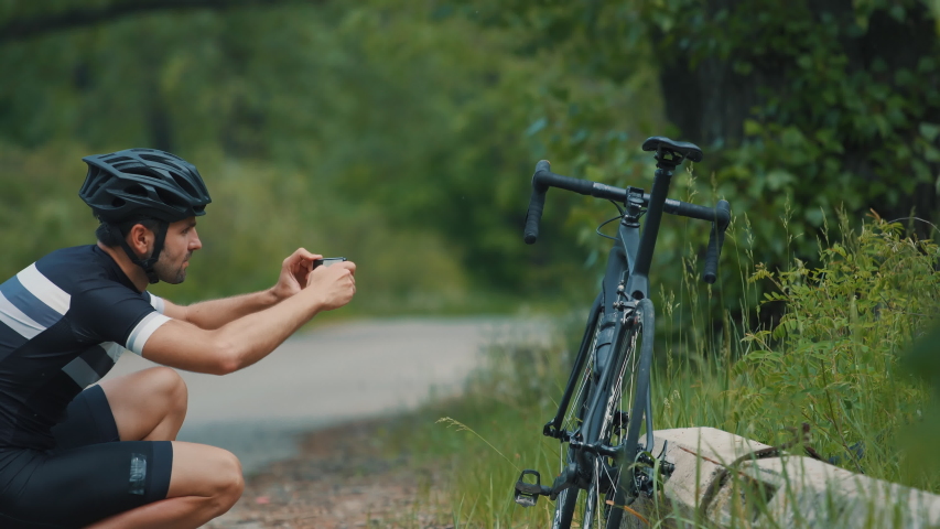Cyclist Taking Photo Of His Bicycle.Athlete Photograph His Bike.Cyclist Making Photo His Bike.Bicyclist Using Smartphone.Cyclist Using Phone.Bicyclist Taking Photo.Cyclist Takes Pictures Of His Bike.	