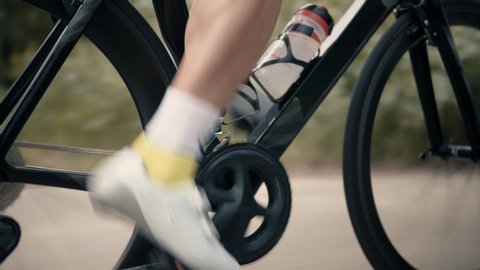 Athlete Cyclist Twists Pedals And Wheel On Road Bicycle.Cycling Triathlon Intensive Cardio Training.Professional Triathlete Workout Exercising.Cyclist Leg And Gear System Cycling Pedaling On ITT.