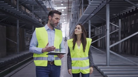 Two engineers walking through factory discussing work related topics