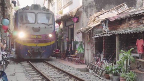 Hanoi, Vietnam - April 18, 2019: Train passing through a narrow street of the Hanoi Old Quarter. The Hanoi Train Street is a popular tourist attraction of Asia.