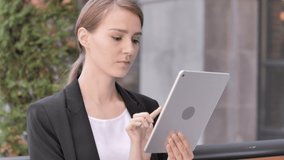 Video Chat on Tablet by Young Businesswoman Sitting Outdoor