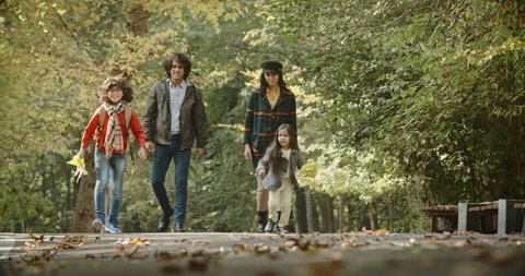 Young asian family of four walking down the road in golden autumn park, cheerfuly smiling - 4k Stock Video