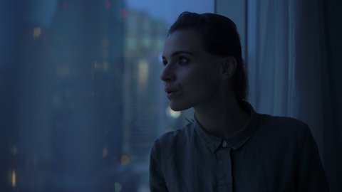 Pensive, elegant woman admire view form window at home in the evening