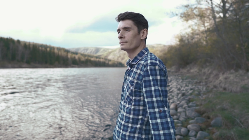 Tourist hiker businessman talking on the phone at the mountain river in nature on a summer evening. Concept communication in hard-to-reach places