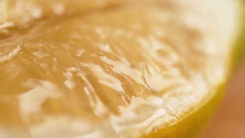 SLOW MOTION, MACRO, DOF: Droplets of refreshing water fall onto the aromatic lemon slice. Drops of freshly squeezed lemon juice fall onto the piece of an organic lemon. Fragrant homegrown fruit.