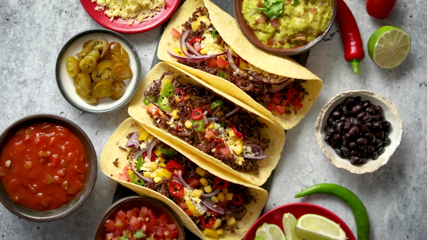 Tasty Mexican meat tacos served with various vegetables and salsa. With sides in ceramic bowls around. Top view composition. Royalty-Free Stock Footage #1030272806