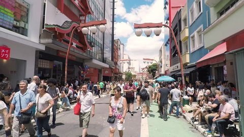 Sao Paulo SP, Brazil - March 03, 2019: People at the stores and commerce on the Galvao Bueno street, at Liberdade neighborhood. Street with japanese thematic, oriental decorations. Tourist spot.
