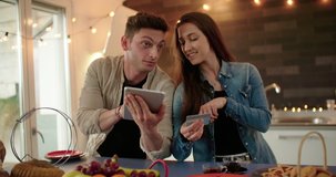Young adult couple doing online shopping together in the kitchen. shot in slow motion	
