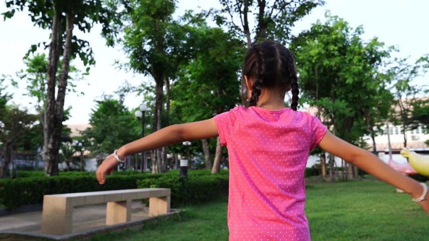 Slow motion shot : Asian girl spinning happily in the park in summer 