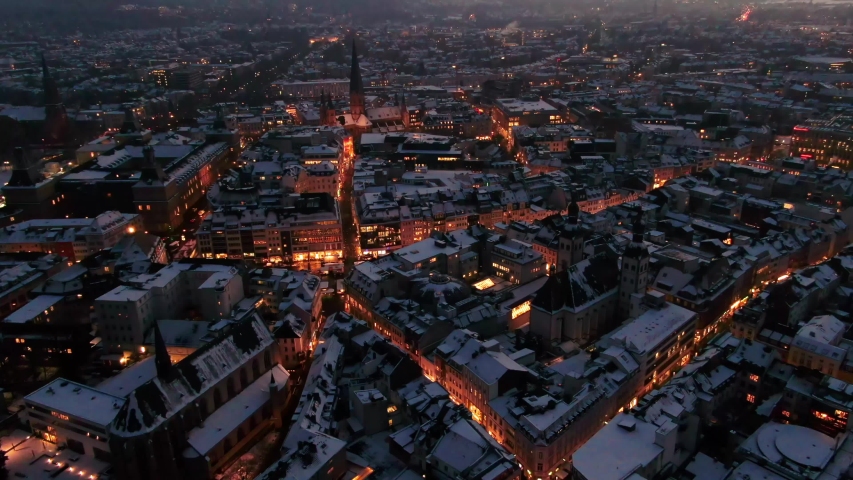 Aerial shot of Bonn city at night in winter. Snow covered city at night. city lights at night, German-city covered in snow, night drone shot of city at-night covered in snow.