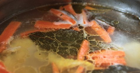 Fish soup is boiling in a pot on the kitchen