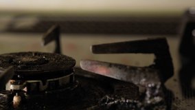 Switching on old kitchen stove gas burner. Selective focus. Panning to the left.
