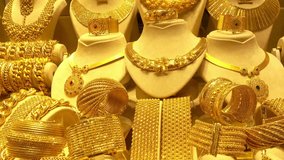 A lot of gold jewelry on the shop window. Gold bracelets rotate on stands