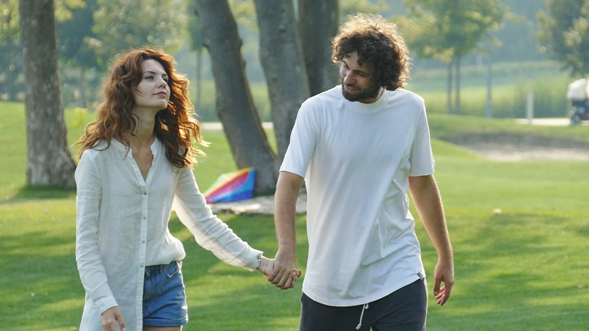 Happy couple walking and having fun outdoors in the park. Slow motion.