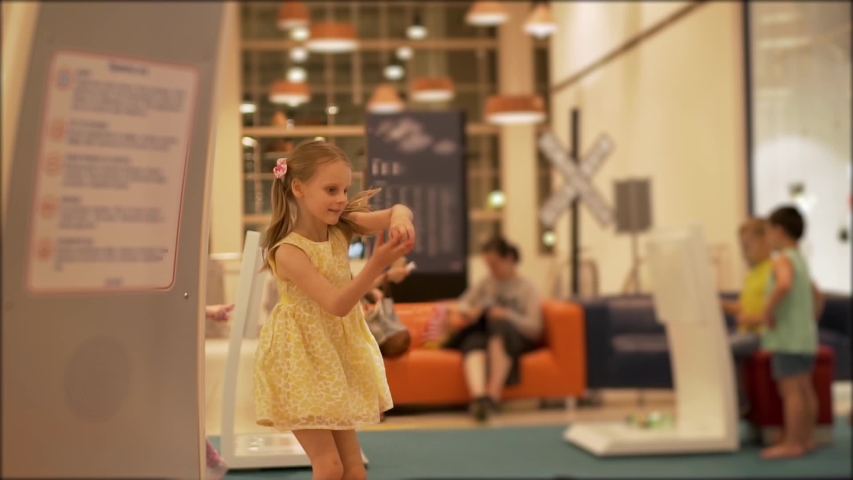 Blonde girl in yellow dress dancing and having fun at the Mall