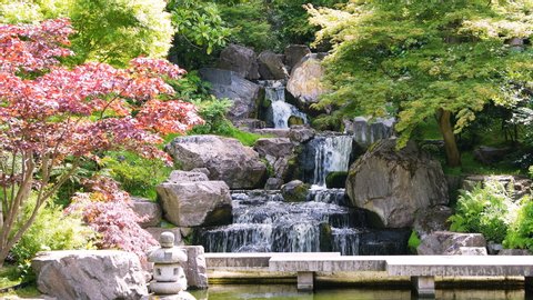 Waterfall with maple trees in Kyoto Japanese Garden in Holland Park green summer peaceful zen lake pond water and green trees in London, UK with nobody