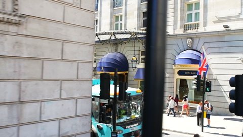 London, UK - June 22, 2018: High angle slow motion point of view pov driving in car on Piccadilly circus street road, Ritz-Carlton hotel and people walking by cigar shop store, police guard on horses