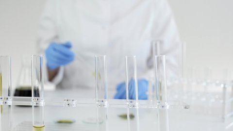 Closeup of a female scientist in a laboratory working on experiment with CBD oil extracted from a marijuana plant. Titration of the oil in a glass tube.
