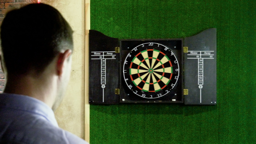 Man throwing a dart arrow in target center of dartboard in game of darts. 4K Royalty-Free Stock Footage #1030343090