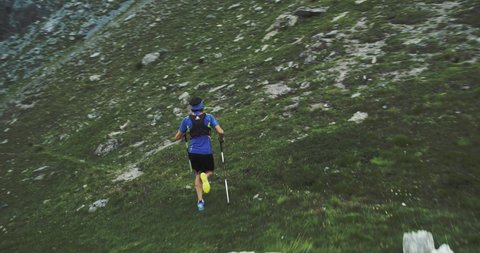 Man climbing run on mountain rise.Trail runner running to top peak training on rocky climb.Wild green nature outdoors in cloudy foggy bad weather. Activity,sport,effort,challenge,willpower concepts