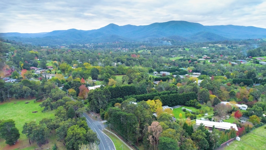 Forward flight over rural road and houses towards beautiful mountains. Healesville, Victoria, Australia