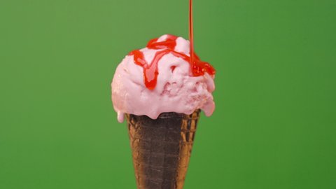 Melting Ice cream in dark cone with strawberry topping on a green background