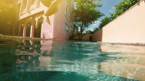 Woman in pink bikini jumping into swimming pool in slow motion. 20s. 1080p Slow Motion. Video of young woman swimming in pool. Beautiful woman is wearing goggles.