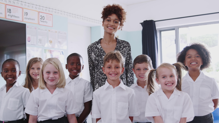 Portrait Of Elementary School Pupils Wearing Uniform In Classroom With Male Teacher | Shutterstock HD Video #1030376225