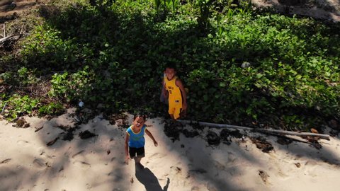 El Nido, Philippines - 12 01 2018: Children playing on a sandy beach, chasing drone.