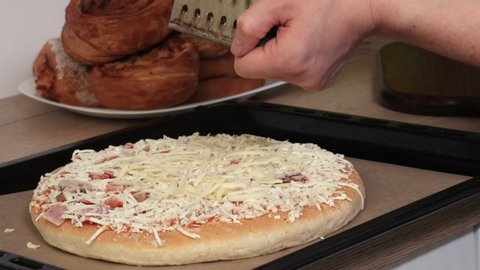 Woman adding a sprinkle of cheese on Pizza close up