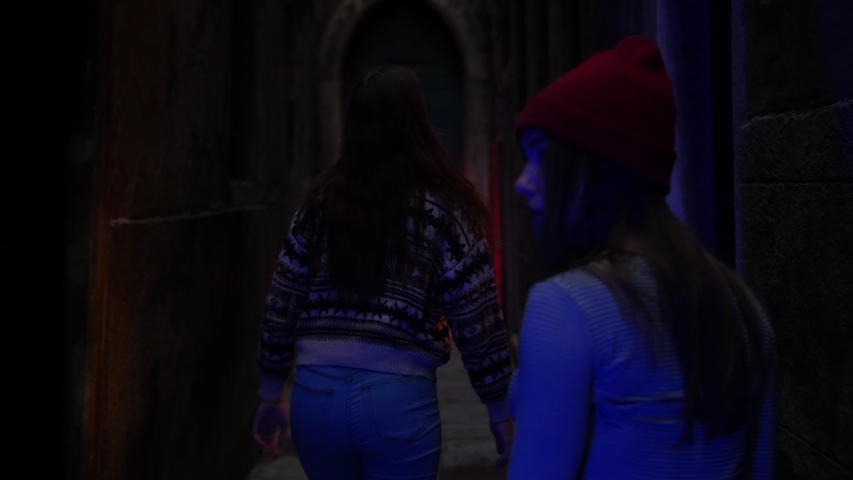 Two young women researchers walking on the dark old mysterious dangerous corridor
