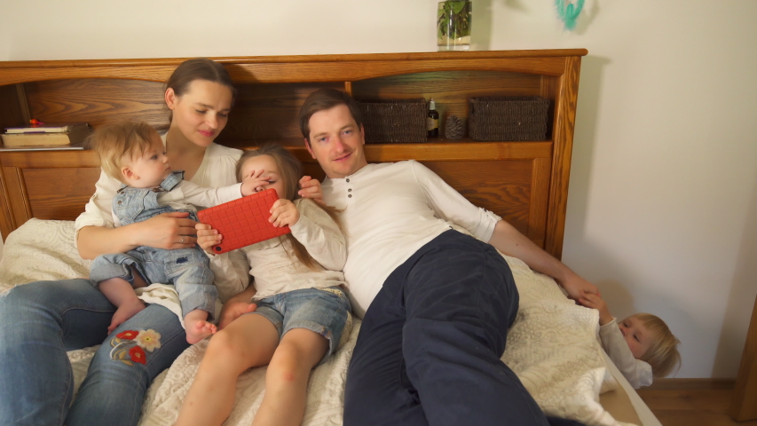 Parents with kids have fun in bed. Handheld motion shot