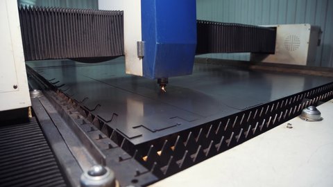 Metal is cut at the plant with the help of a laser, sparks are poured in the place of metal cutting