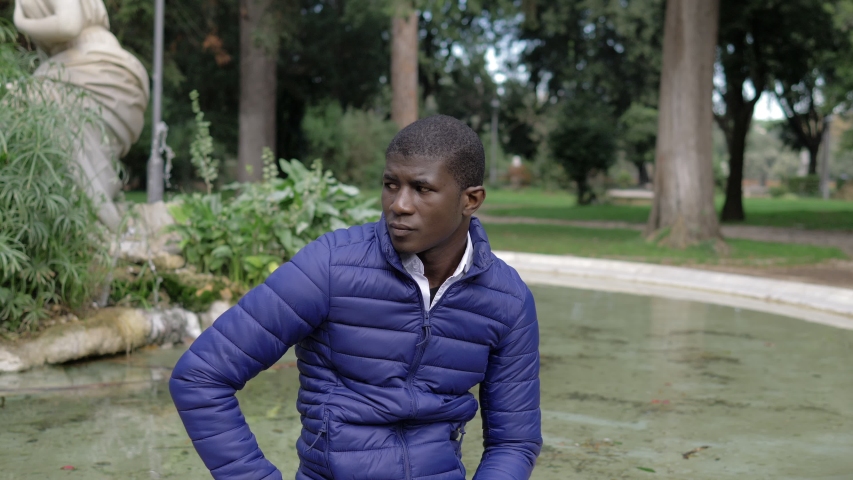 Attractive young black african man turning and smiling at camera in the park