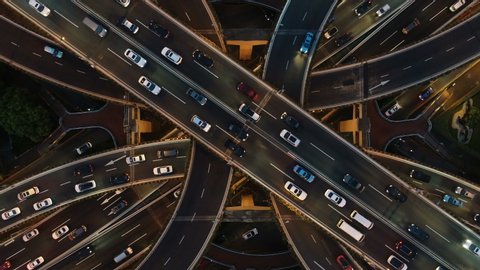 Overhead drone shot of cars driving over elevated highway and busy interchange in Shanghai, China