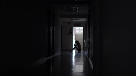 Silhouette of a sad young girl sitting in the dark in old condo, Domestic violence, family problems, Stress, violence, The concept of depression and suicide. Remote image
