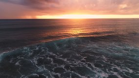 Aerial view of burning sky and golden sunrise over ocean waves, caribbean sea