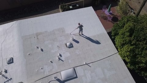 Aerial of a workman applying roof coating