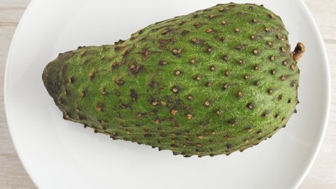 One soursop graviola, exotic, fruit Guanabana on plate, Rotating