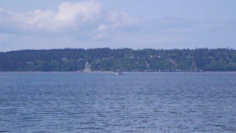 Distant sailboat motoring past beach at Camano Island State Park, Washington State 10sec/24fps slow motion. Version 4