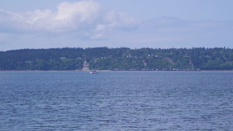 Distant sailboat motoring past beach at Camano Island State Park, Washington State 5sec/60fps