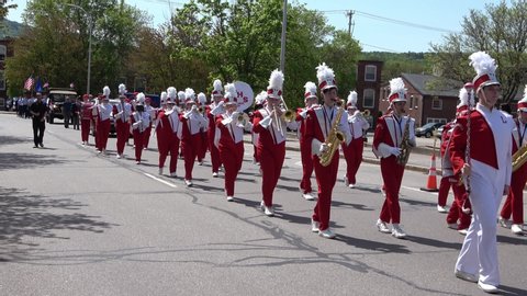 LACONIA, NH / USA - MAY 27 2019: Laconia High School Marching Band in read and white uniforms marches to Veteran's Square at the Memorial Day Parade and celebration. Sync sound.