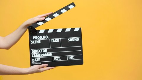 Close up female hold in hand classic director clear empty black film making clapperboard isolated on yellow orange background studio. Cinematography production concept. Copy space advertising mock up.