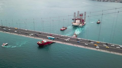 ISTANBUL - CIRCA 2018: Towing convoy consisting of a superstructure of a technological oil platform and tow boats (one main, two aftmost check helm and an auxiliary) passing under the Bosphorus Bridge